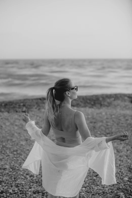 woman in white dress walking on beach with water in background