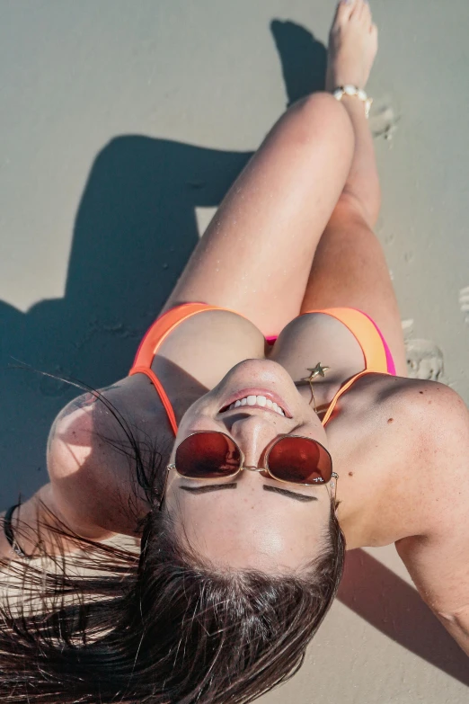 a beautiful young woman in a bikini laying on the sand