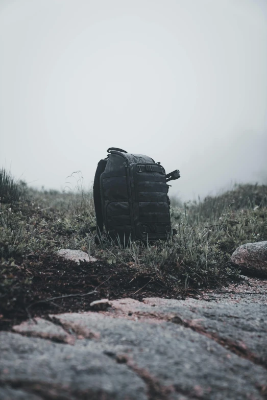 a backpack sitting in a field on a foggy day