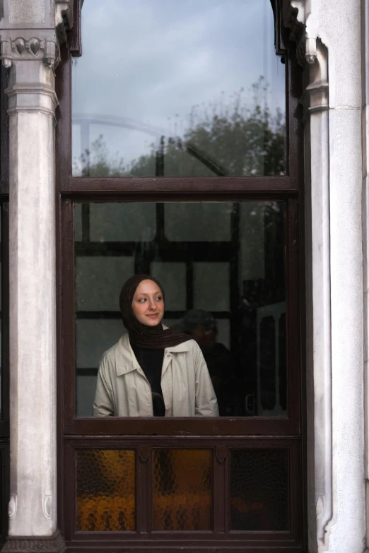 a young woman smiles from behind an iron framed window