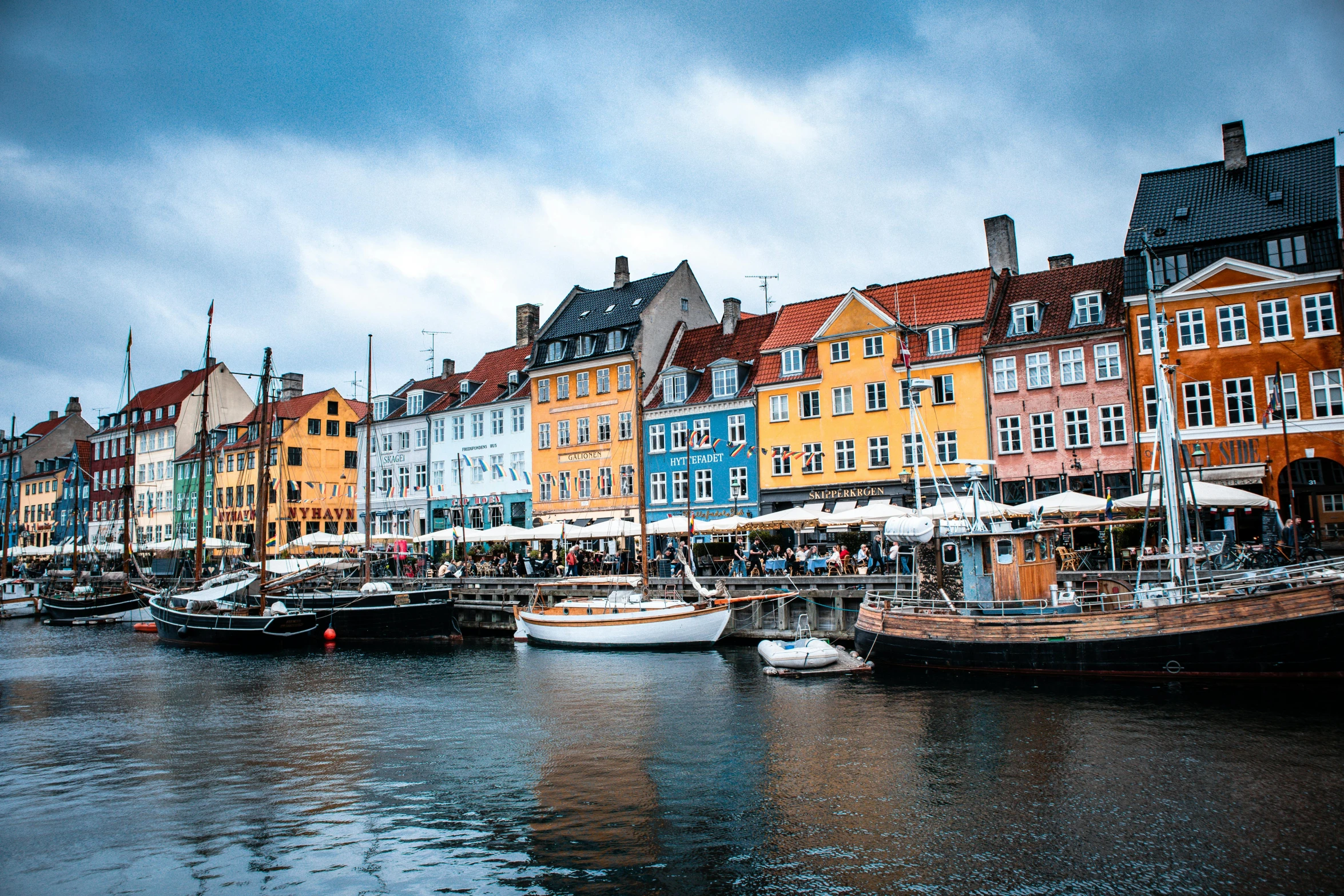 boats in water surrounded by colorful buildings on cloudy day