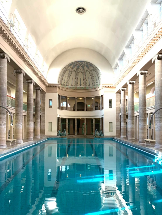 a big swimming pool in a large building with an arched ceiling