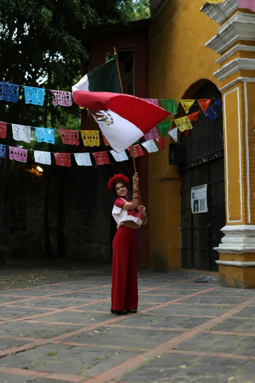 woman in red with mexican flag holding an umbrella on the street