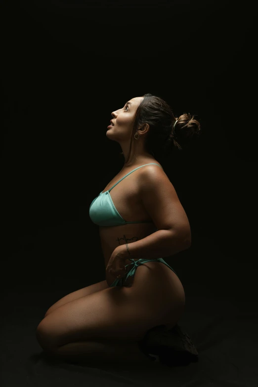 a woman in a bathing suit sitting on a black background