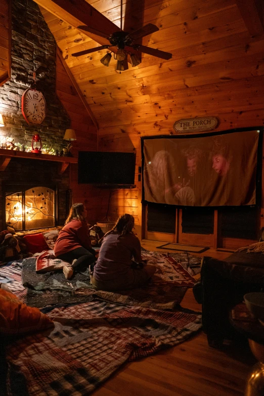 people sitting around a fire place in a rustic cabin