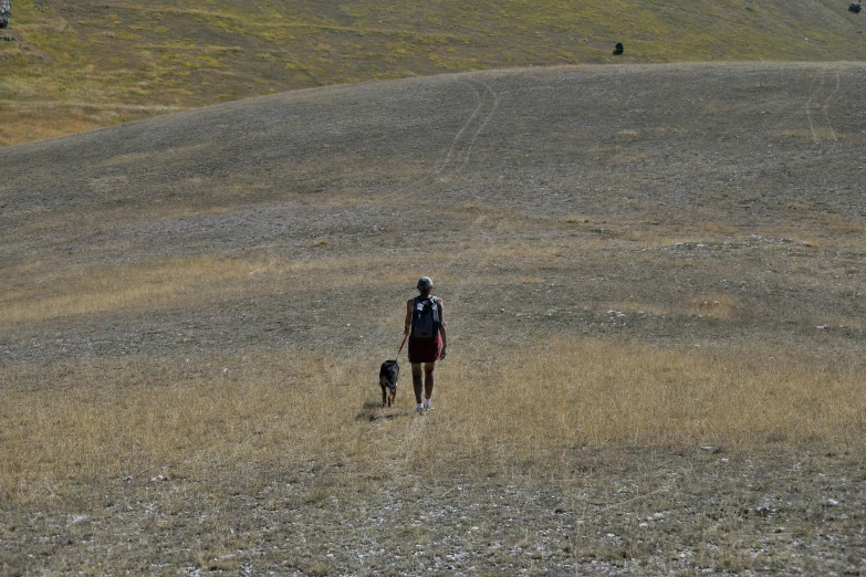 a person wearing safety gear and a backpack walks in a barren area