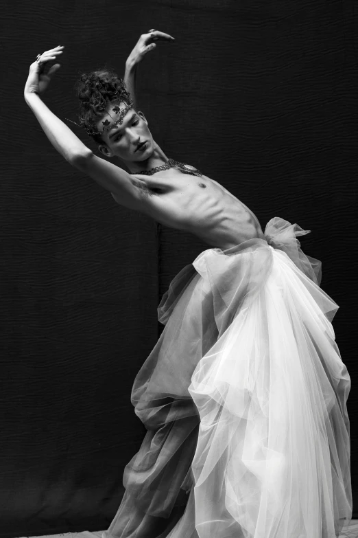 woman in a tulle skirt standing with one hand up and one leg in the air