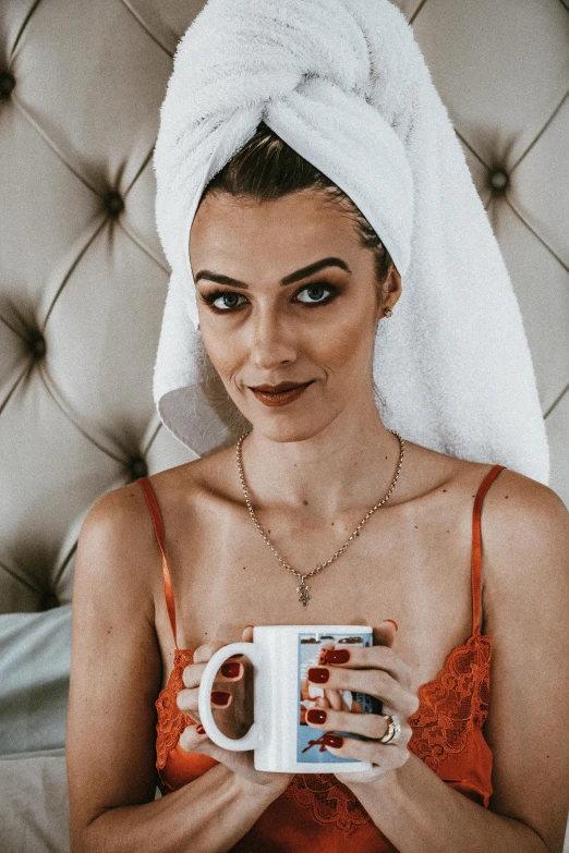 a woman wearing a towel holds a mug in a el room