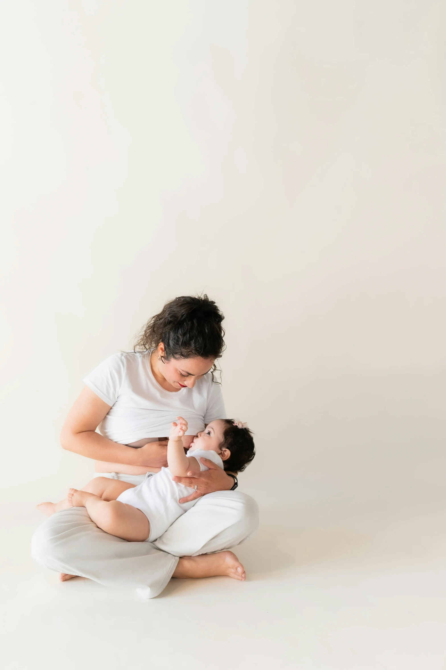 a young woman holding a baby in her lap on the floor