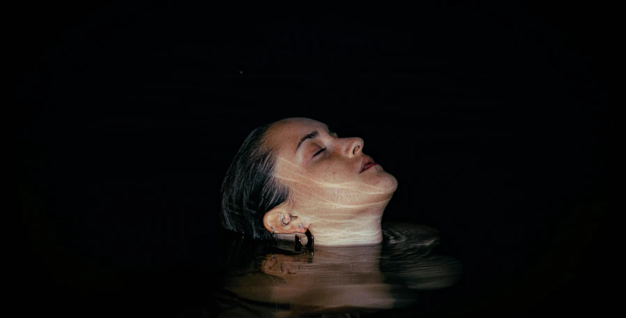 a woman with head above water is in the dark