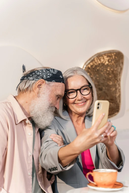 man taking picture of smiling older woman with cellphone