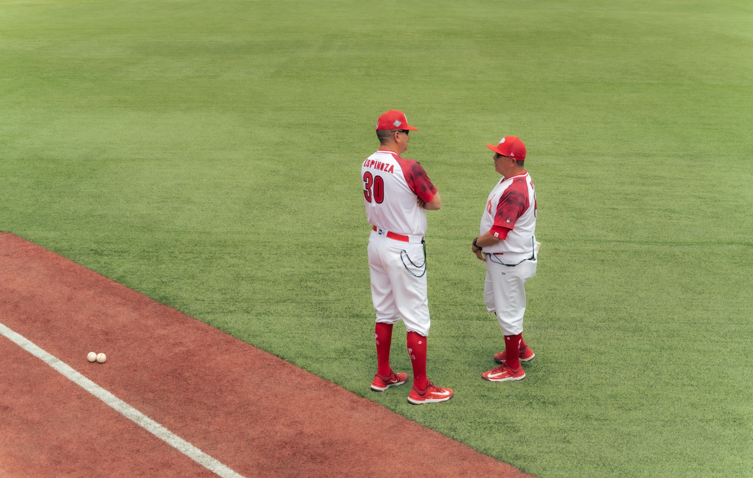 two red sox players stand on the field with their balls