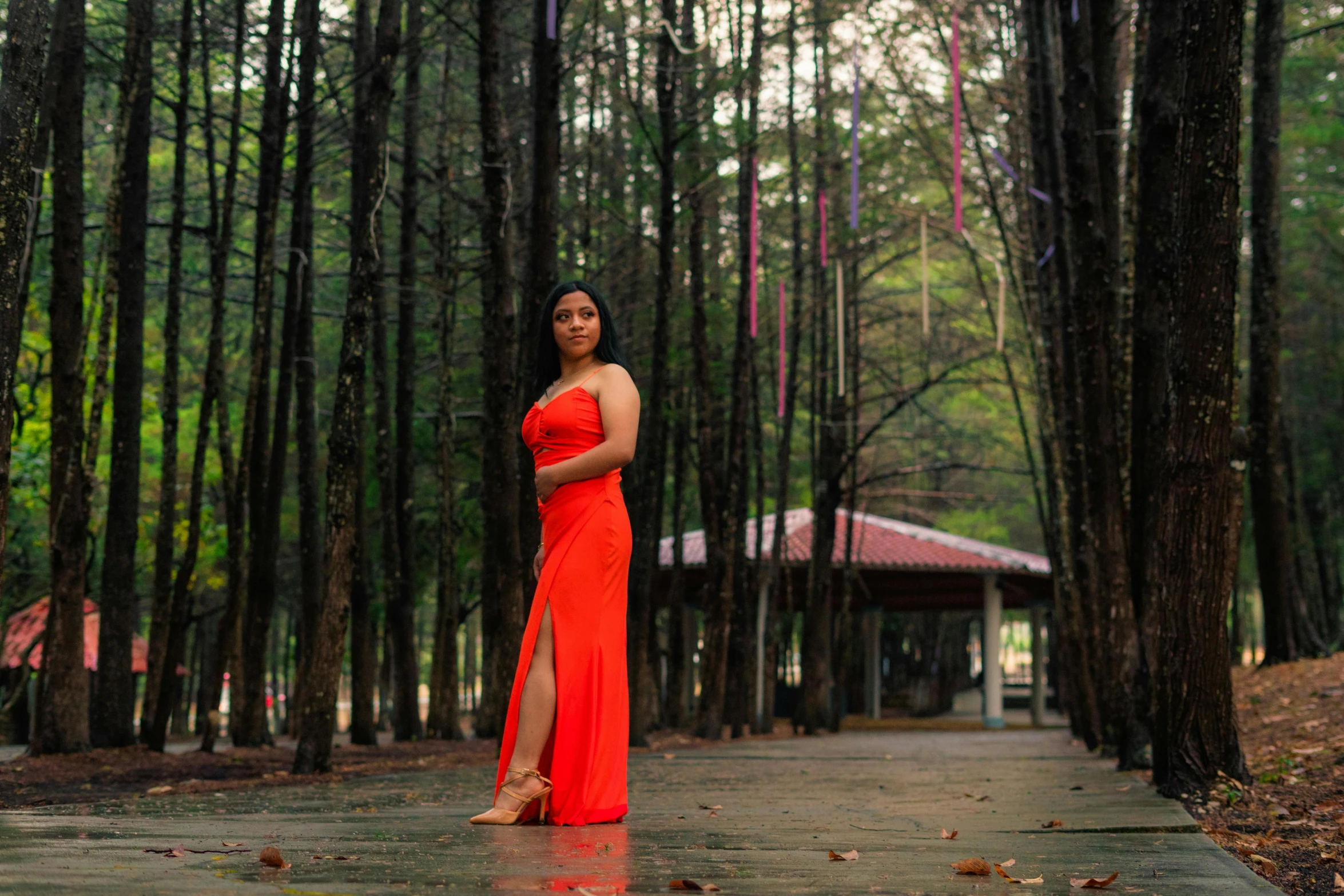 a beautiful woman in an orange dress standing next to a forest