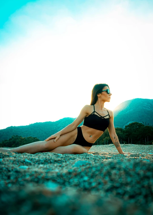 a beautiful woman sitting on a beach near the water