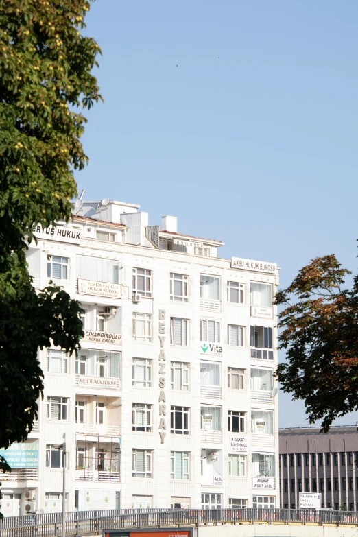 a tall white building with trees on the side