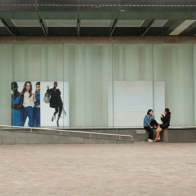 some people are sitting on benches near a wall and some buildings