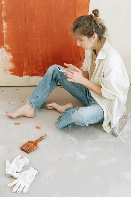 a young woman sits on the floor, rubbing her toe against her leg with other pieces of plastic