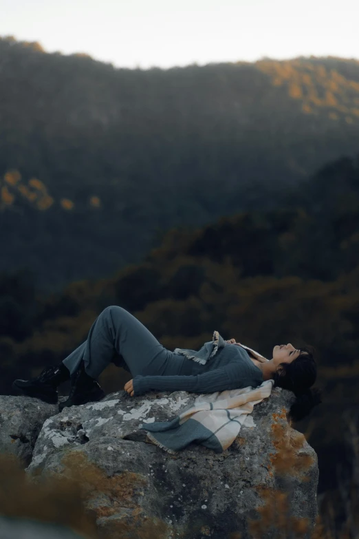 a person lying on a rock on top of a mountain