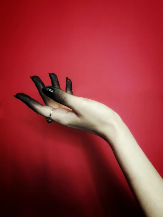 a woman's hand with black nails reaching towards the wall