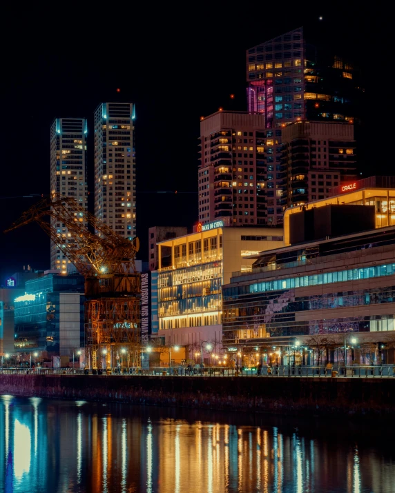 city night scene on the edge of a body of water with skyscrs