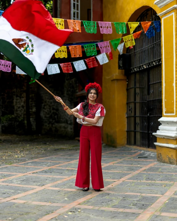 woman in spanish clothing poses with mexican flag on city street