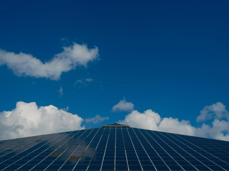 a blue building has a black tiled roof and blue sky with white clouds