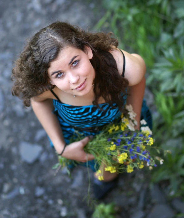 a young lady holding a bouquet of wildflowers and flowers