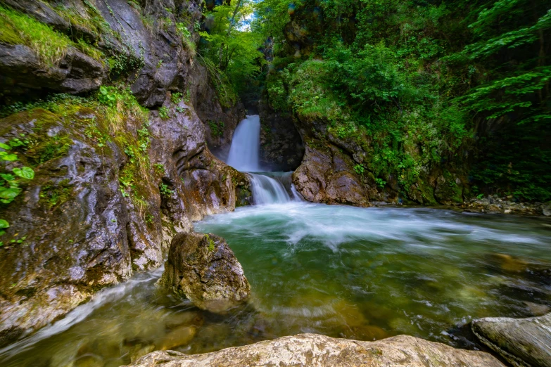 a small waterfall running over rocks into a small river