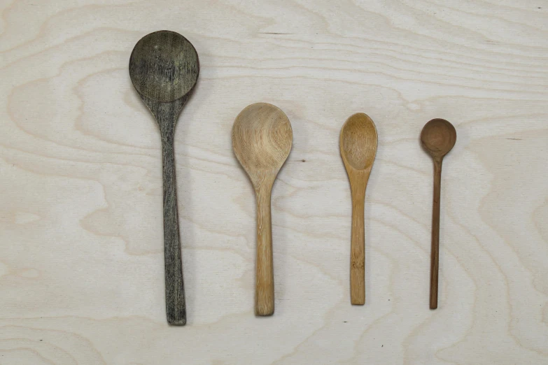 wooden spoons and spoon knives lined up on top of a white surface