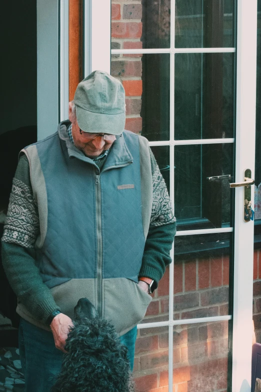 a man wearing a blue jacket is holding a black dog