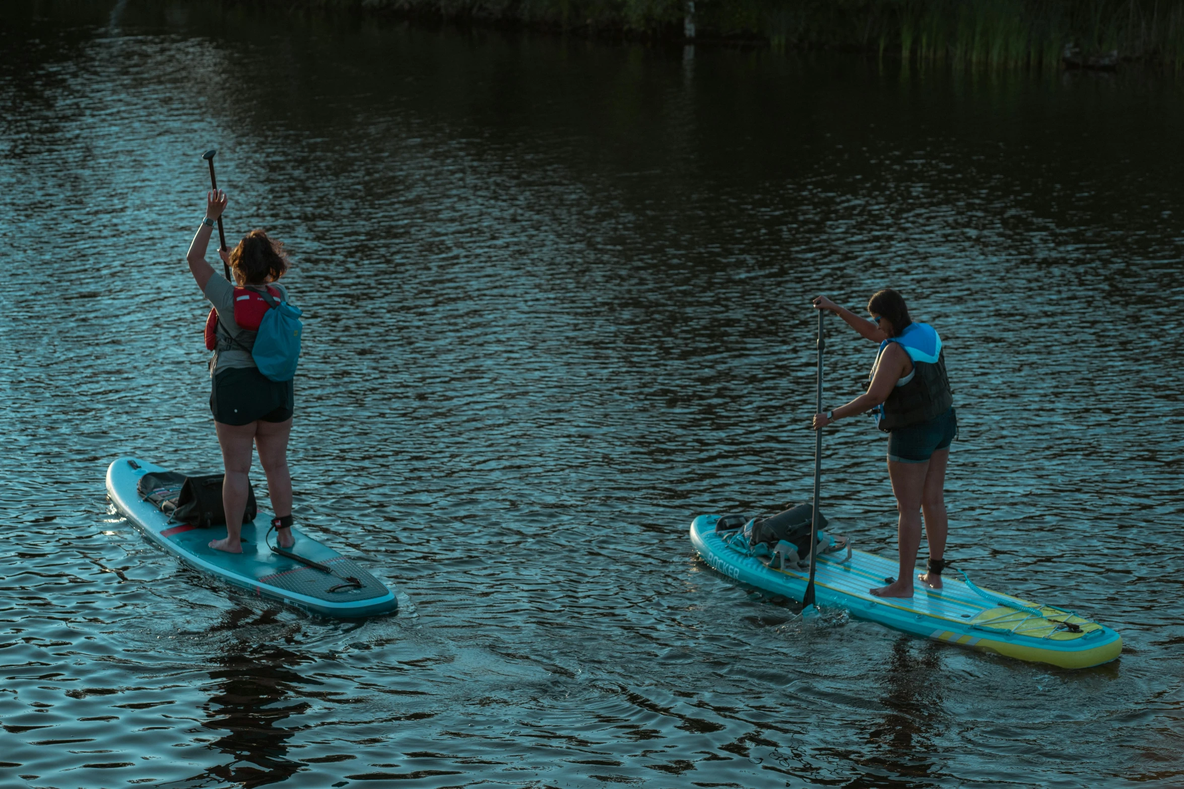 a man and woman standing on paddle boards in water