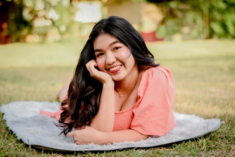 a smiling girl laying on top of a white blanket