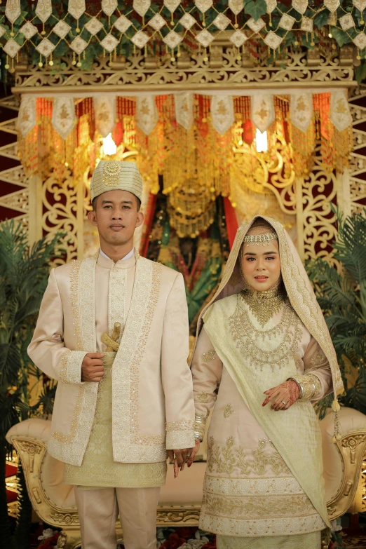 two brides wearing indian outfits stand in front of a decorated stage