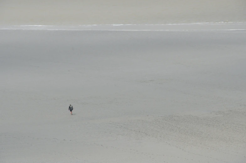 two people walking through a sandy area together