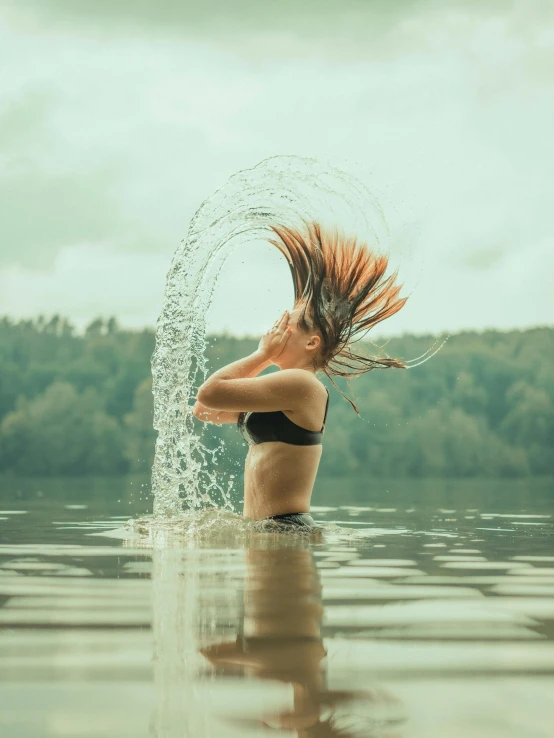 woman in water with splashing hair and hands on water