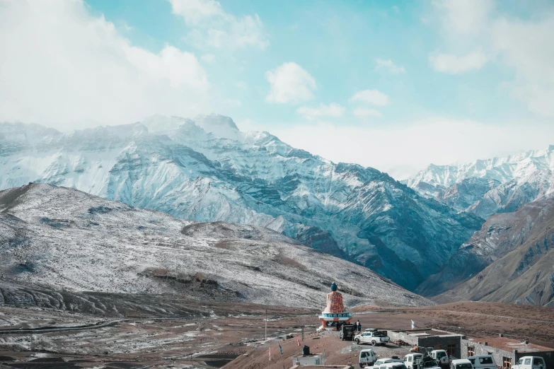 a man standing on top of a dirt hill next to a large mountain range