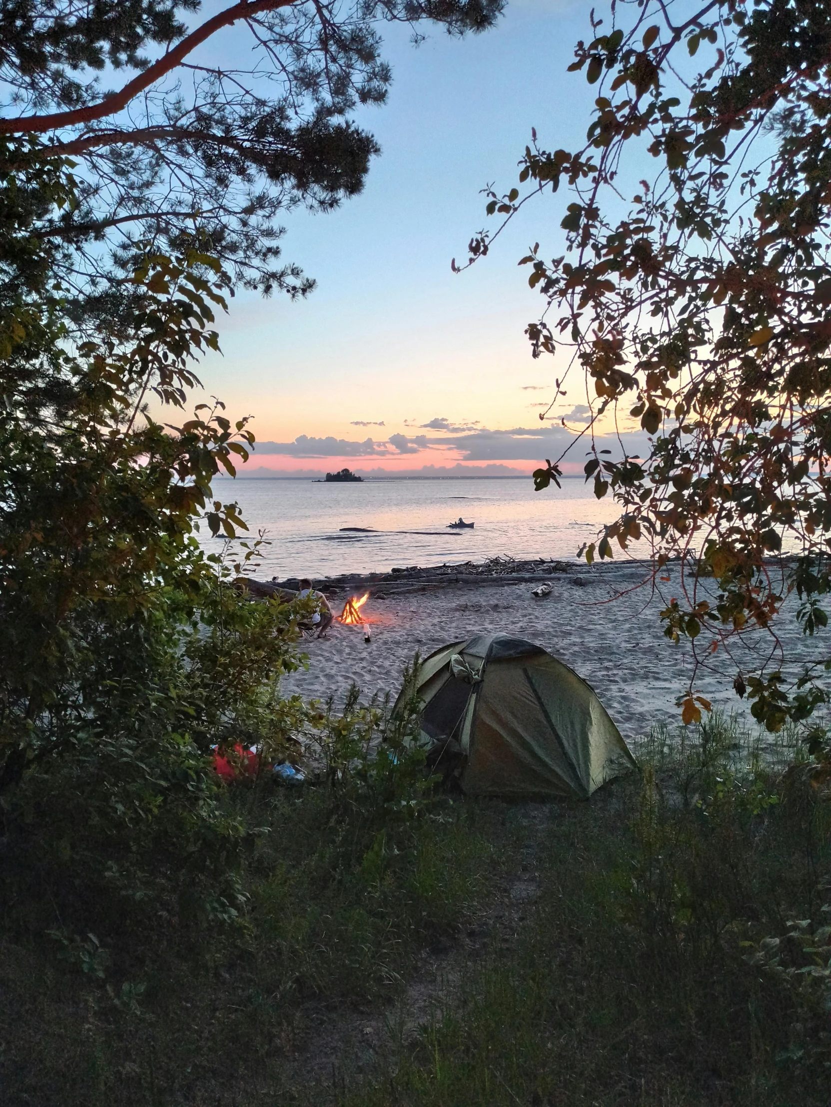 an open tent set up on the shore at sunset