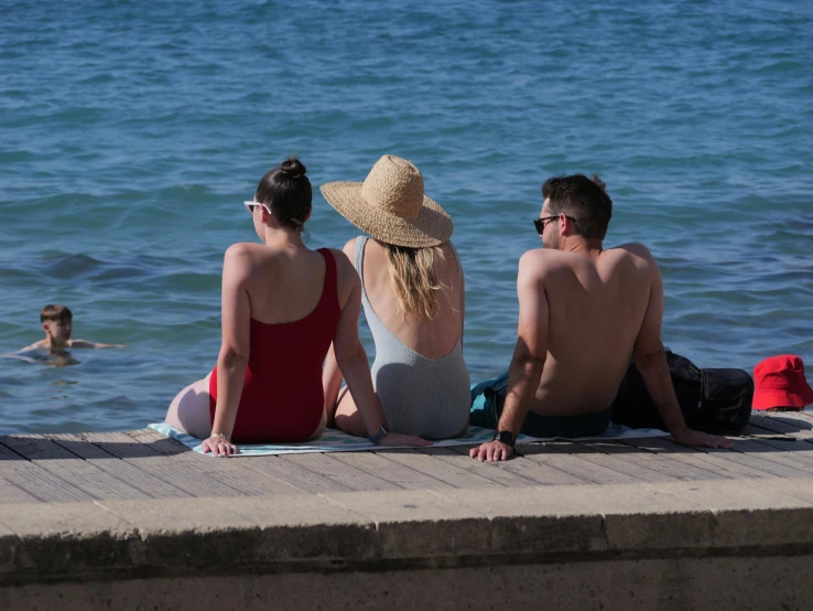 a group of people sitting on the pier near the water