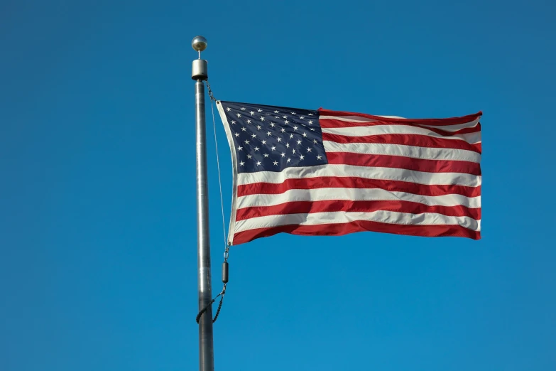 an american flag flying in the sky on a pole