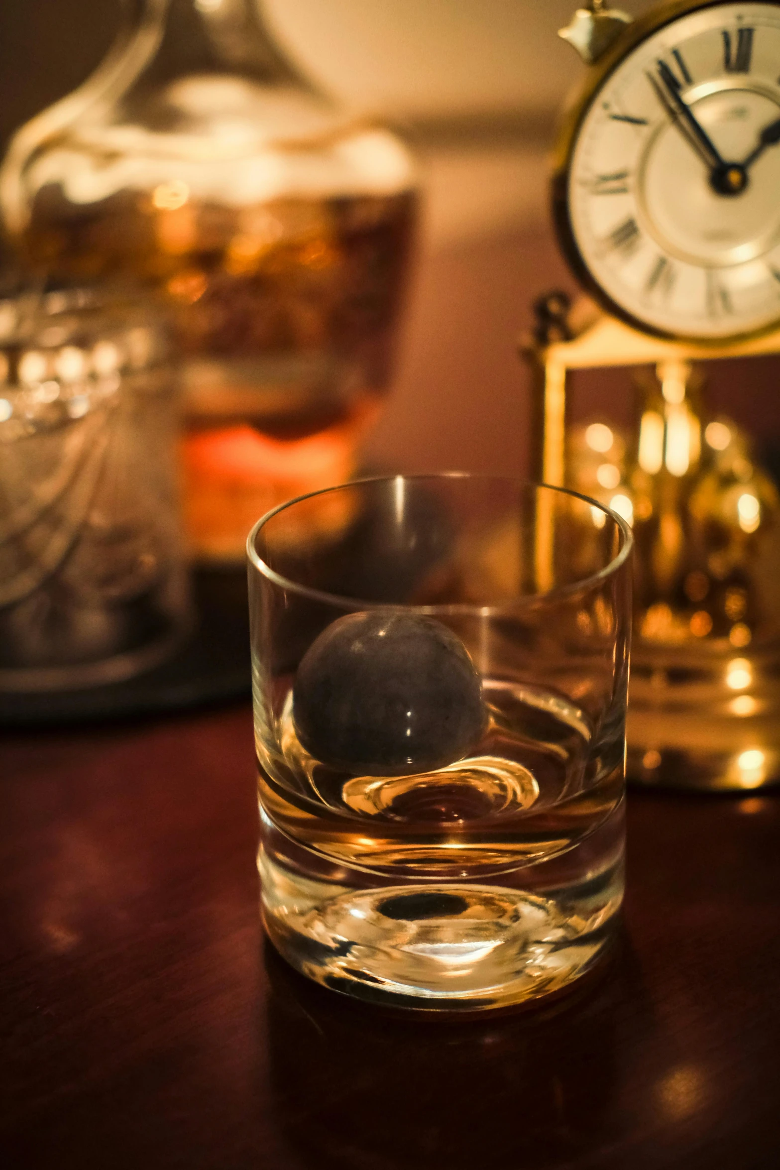 a glass filled with water and an olive on a table