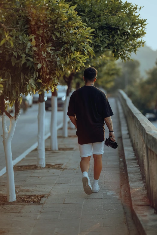 a man walking along side of a street while holding his arm up