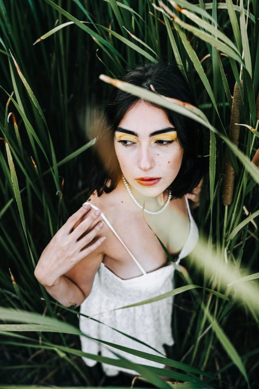 a woman with long dark hair standing in the tall grass