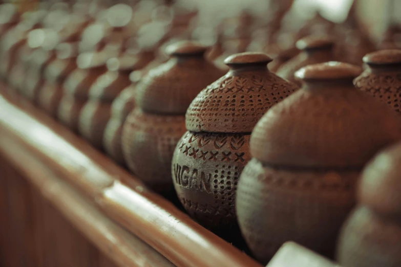 four brown pottery jars lined up on a shelf