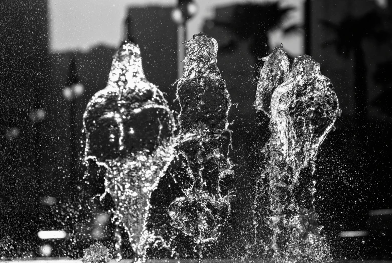 an artistic po of some water fountains in front of a city skyline