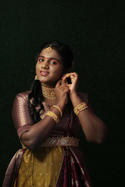 woman in yellow with gold jewellery and dress holding her hair