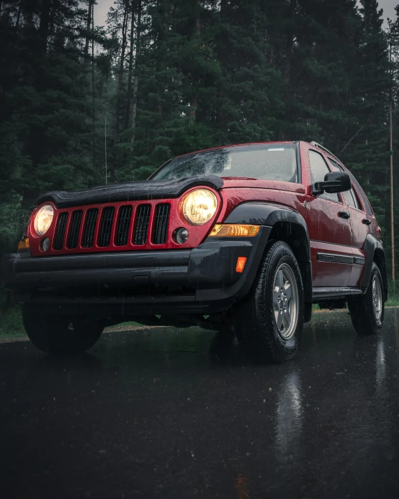 a red jeep is parked near a forest