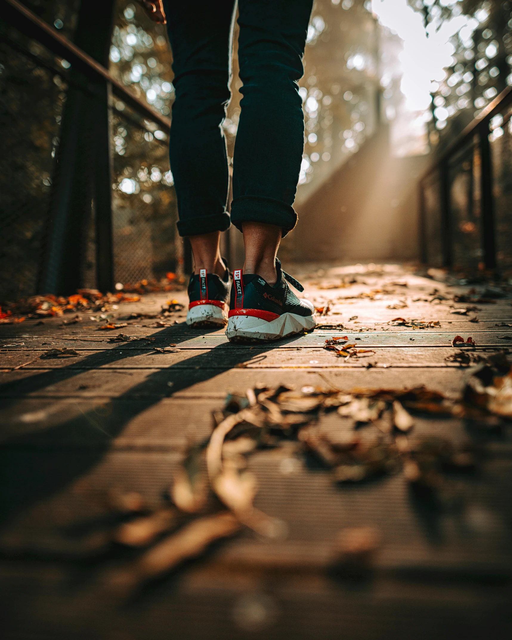 two people walking along the sidewalk in front of trees