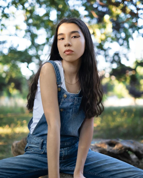 an asian woman with dark hair sitting on top of a log