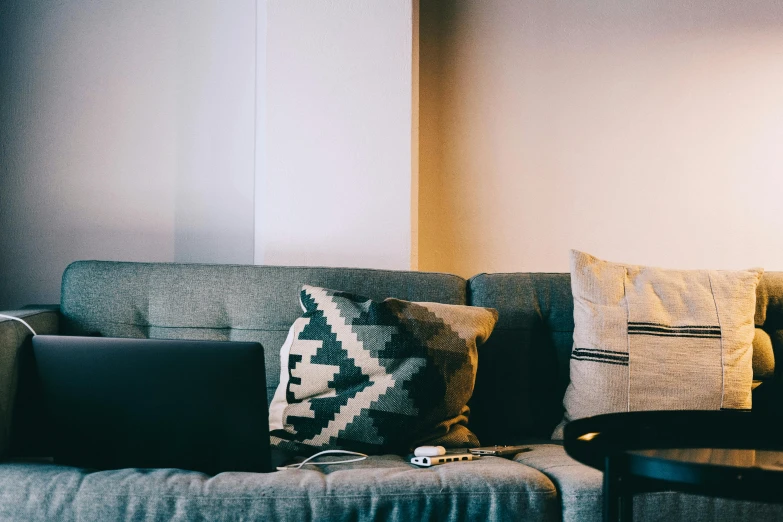 two pillows are sitting on a couch in front of a laptop