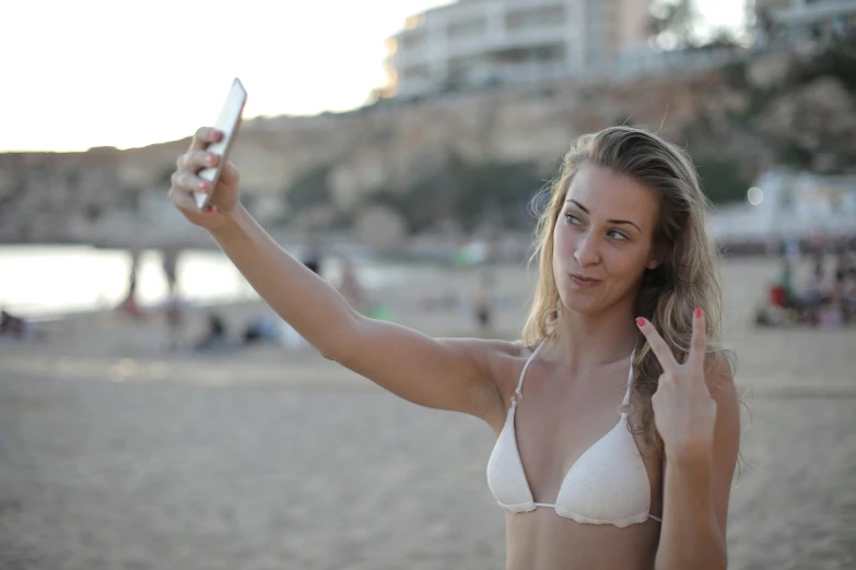 woman holding a camera taking a po on the beach